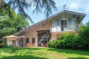 A two-story house with a balcony, a patio with outdoor furniture, and a well-maintained garden. - Villa Bichipau Park - Welkeys (Bidart)