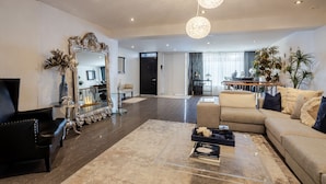 A spacious living room with a large mirror, a sofa, a coffee table, and a chandelier.