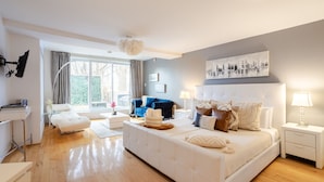 A modern bedroom with a large bed, a desk, and a blue sofa.