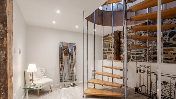 A modern interior with a spiral staircase, a glass table, and a white sofa.