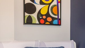 Una cama con un cojín azul y una colcha blanca.