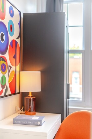 Una camera d'albergo con una lampada moderna, un quadro astratto dai colori vivaci e vista sull'esterno.