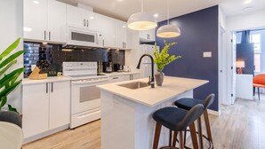 Una cocina moderna con armarios blancos, una isla central, un microondas y una estufa.