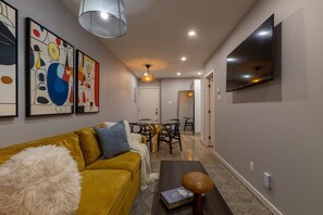 A modern living room with a sofa, a coffee table, and a dining area with a table and chairs. - Beautiful 3BR in Plateau Mont-Royal (Montréal)