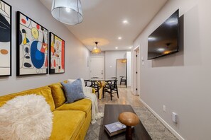 Un salon moderne avec un canapé, une table basse et un téléviseur fixé au mur.