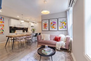 Un salon moderne avec un canapé, une table basse et un coin repas, la cuisine étant visible à l’arrière-plan.