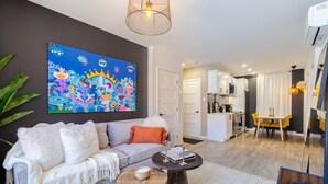 A modern living room with a sofa, coffee table, and a colorful abstract painting on the wall. - Elegant Living: 3-Bedroom in Plateau MTL (Montréal)