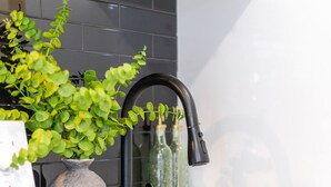 A modern kitchen with a black faucet, a potted plant, and a vase with bottles. - Stunning 3BR in Plateau Mont-Royal (Montréal)