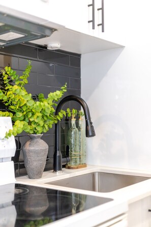 A modern kitchen with a black faucet, a potted plant, and a vase with bottles. - Stunning 3BR in Plateau Mont-Royal (Montréal)