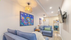 A modern living room with a sofa, a blue armchair, a fluffy white rug, and a colorful abstract painting on the wall. - Stunning 3BR in Plateau Mont-Royal (Montréal)