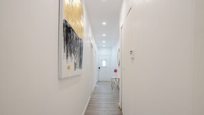 Un couloir avec un plancher en bois, des murs blancs et une porte au fond.