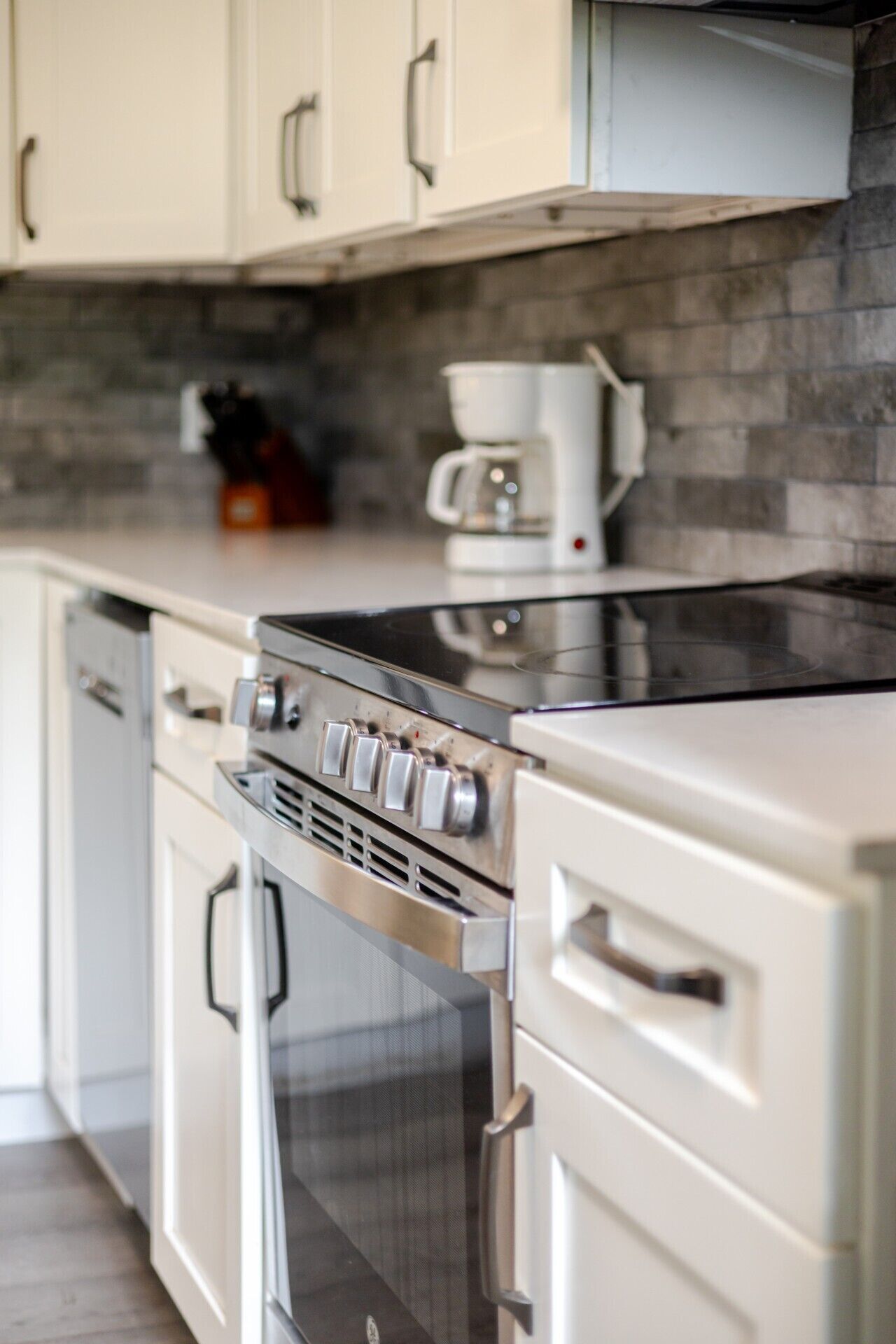 Een keuken met een roestvrijstalen fornuis, oven en koffiezetapparaat op het aanrecht.