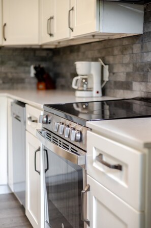 A kitchen with a stainless steel stove, oven, and a coffee maker on the countertop.