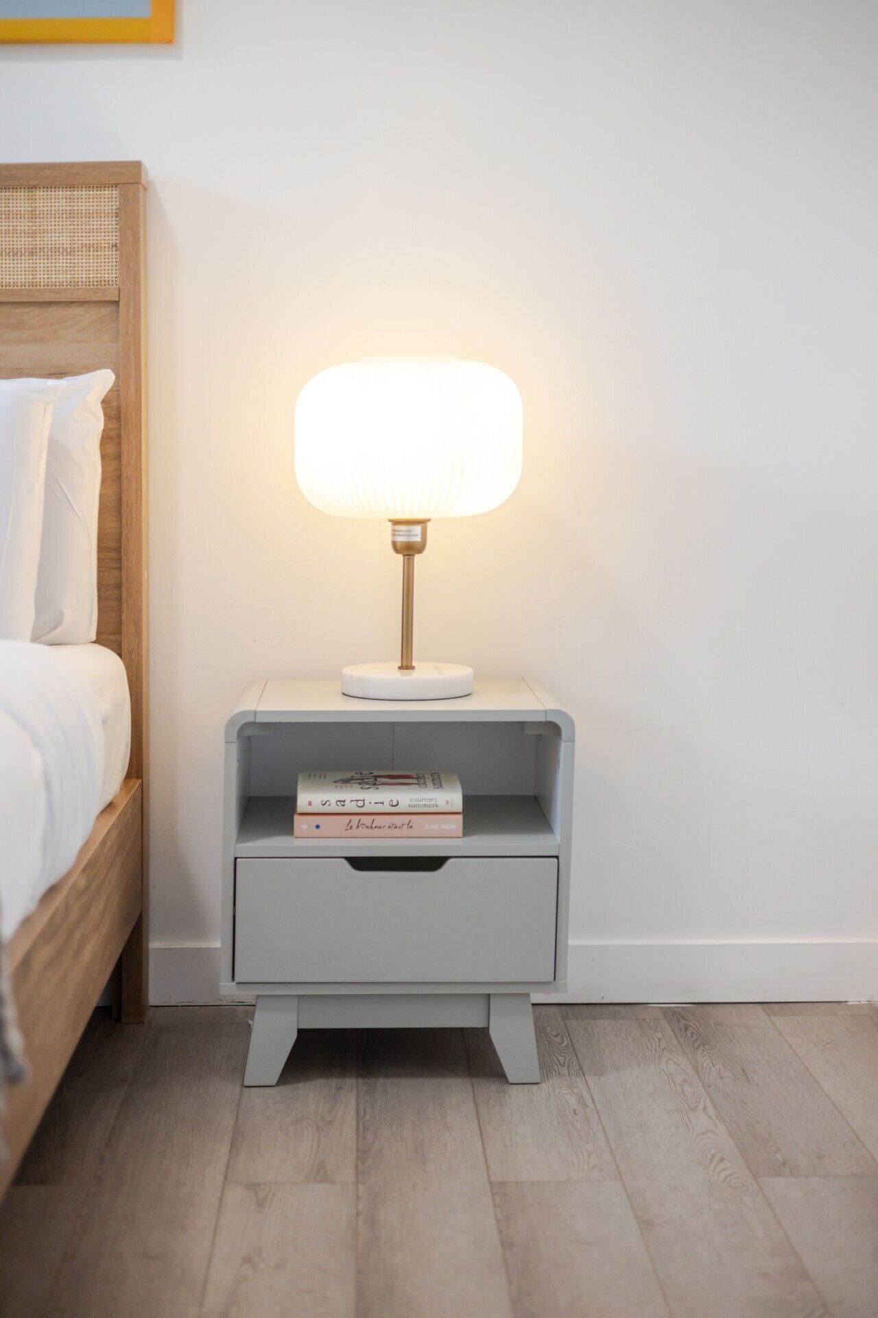 Ein Nachttisch mit Lampe, Schublade und einem Stapel Bücher.