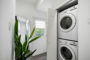 Laundry room with two front-loading washing machines and a potted plant.