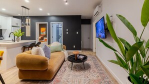 A modern living room with a sofa, a coffee table, and a television. - Vibrant 4BR/2BA Retreat in the Plateau (Montréal)