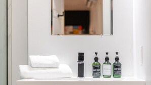 A bathroom vanity with a mirror, a towel, and three bottles of toiletries. - Vibrant 4BR/2BA Retreat in the Plateau (Montréal)