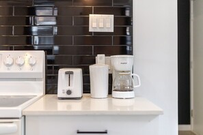 A kitchen with a white countertop, a toaster, a coffee maker, and a stove.