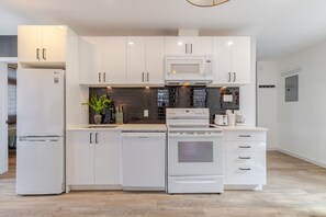 A modern kitchen with white cabinetry, a built-in microwave, a stove, and a dishwasher.