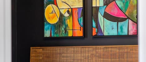 Une chambre à coucher avec un lit, une tête de lit et deux tableaux abstraits accrochés au mur.