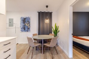 A modern dining area with a round table, four chairs, a pendant light, and a potted plant. - The Perfect Downtown Hideaway (Montréal)