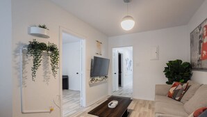 Ett modernt vardagsrum med en soffa, ett soffbord, en tv och växter.