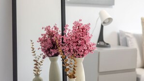 En spegel som reflekterar två vaser med rosa blommor, placerade på ett svart underlag.