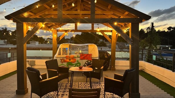 An outdoor patio with a wooden pergola, string lights, and a table with chairs.