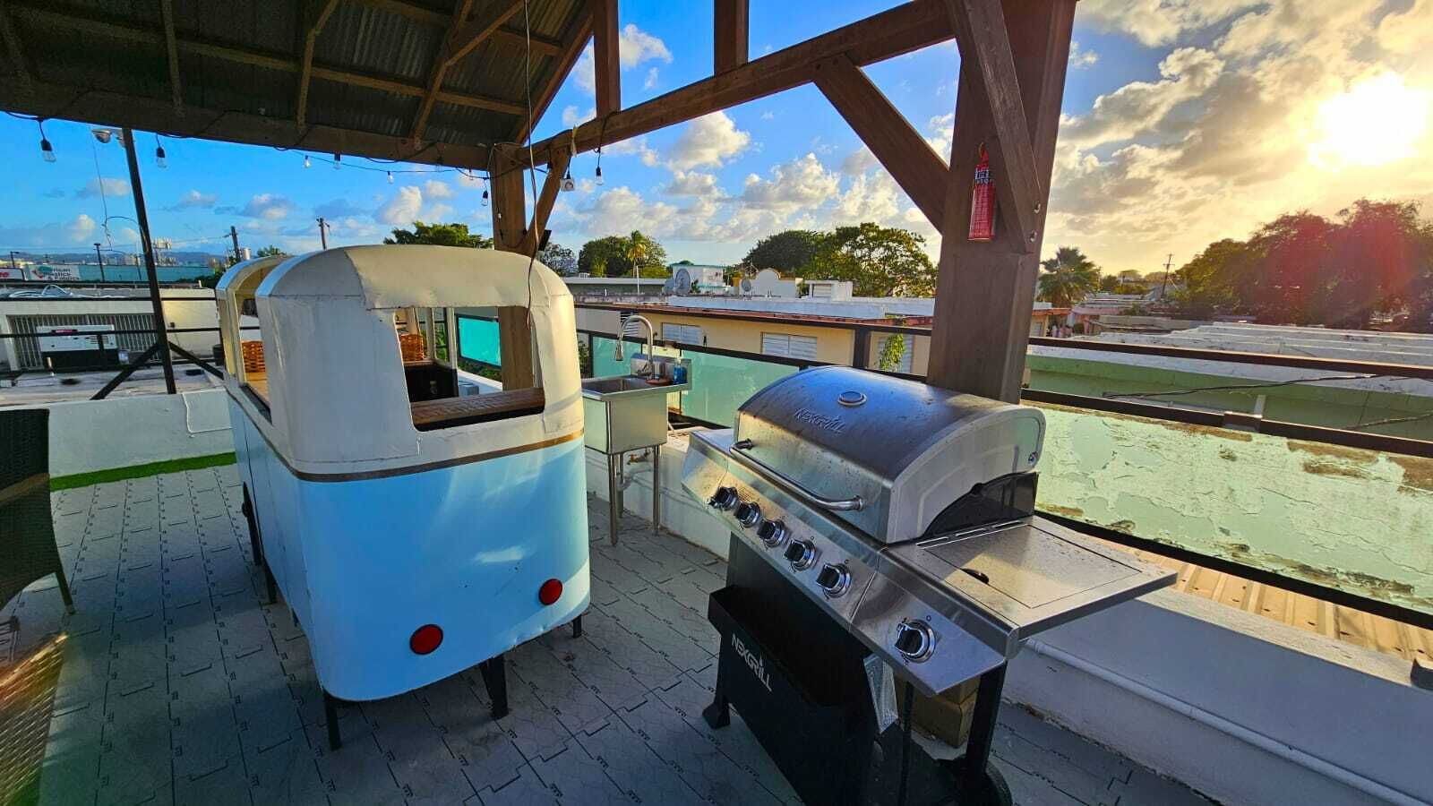 Un espace extérieur abrité équipé d’une cuisine mobile comprenant un barbecue et un réfrigérateur.