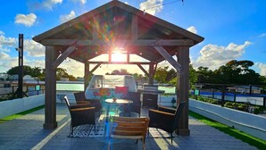 An outdoor patio with a wooden pergola, a grill, and seating.