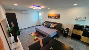 A modern bedroom with a bed, bedside tables, a desk, and a coffee machine.