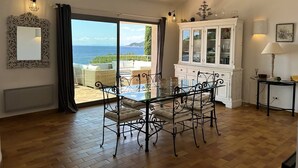 Una habitación amplia con un gran ventanal corredera que da a un balcón con vistas al mar.