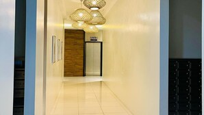 A modern hotel corridor with a polished floor, a wooden door, and a sign indicating an elevator. -  A spacious 31sqm studio unit in abreeza place (Davao City)