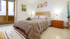 A bedroom with a bed, a nightstand, a lamp, a window, and a door. - Apartment 'El Compromiso' with Balcony, Wi-Fi and Air Conditioning (Caspe)