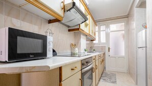 A kitchen with a microwave, oven, and sink. - Apartment 'El Compromiso' with Balcony, Wi-Fi and Air Conditioning (Caspe)