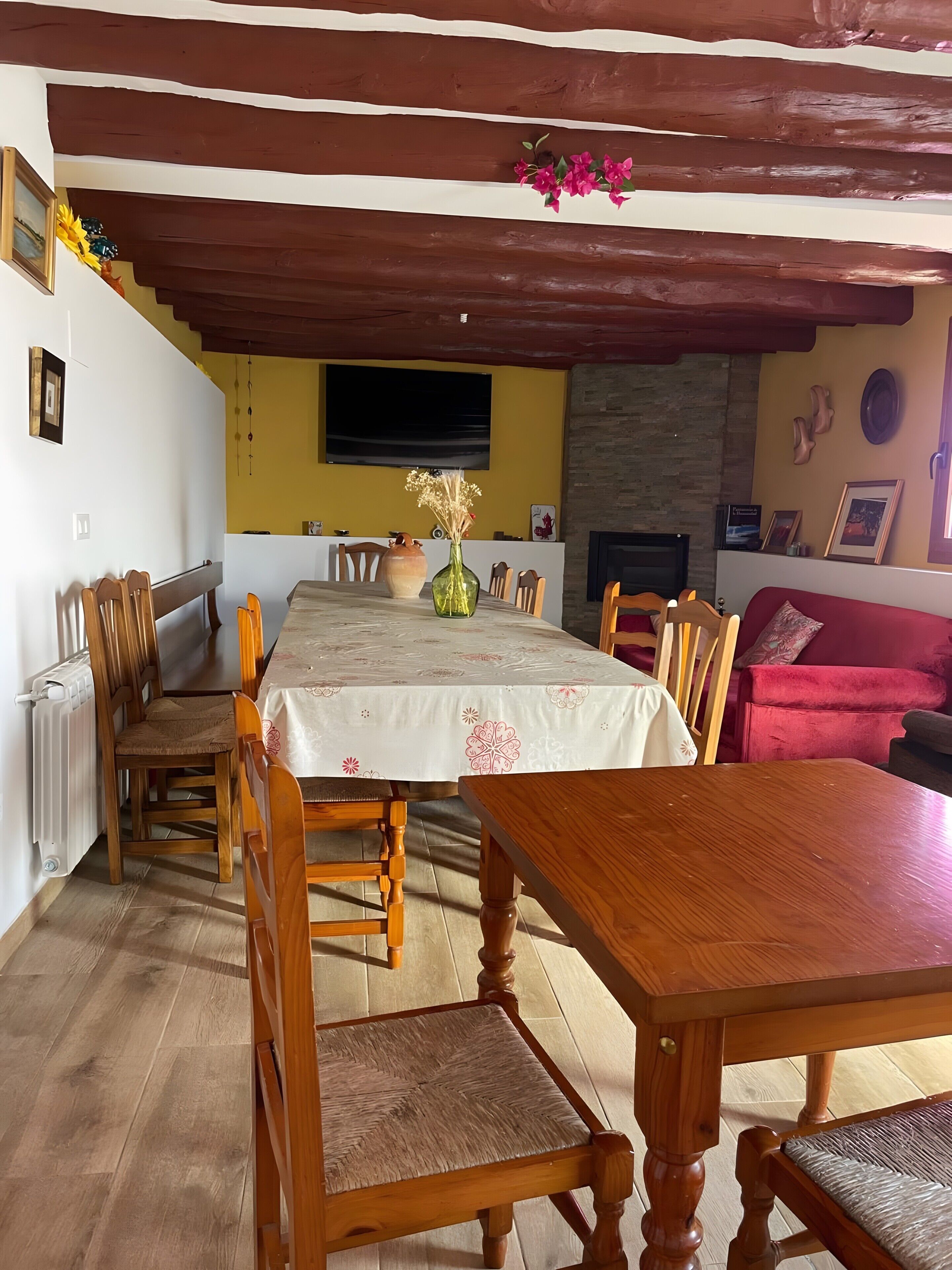 Un coin repas avec une table et des chaises en bois, un téléviseur fixé au mur et une cheminée.