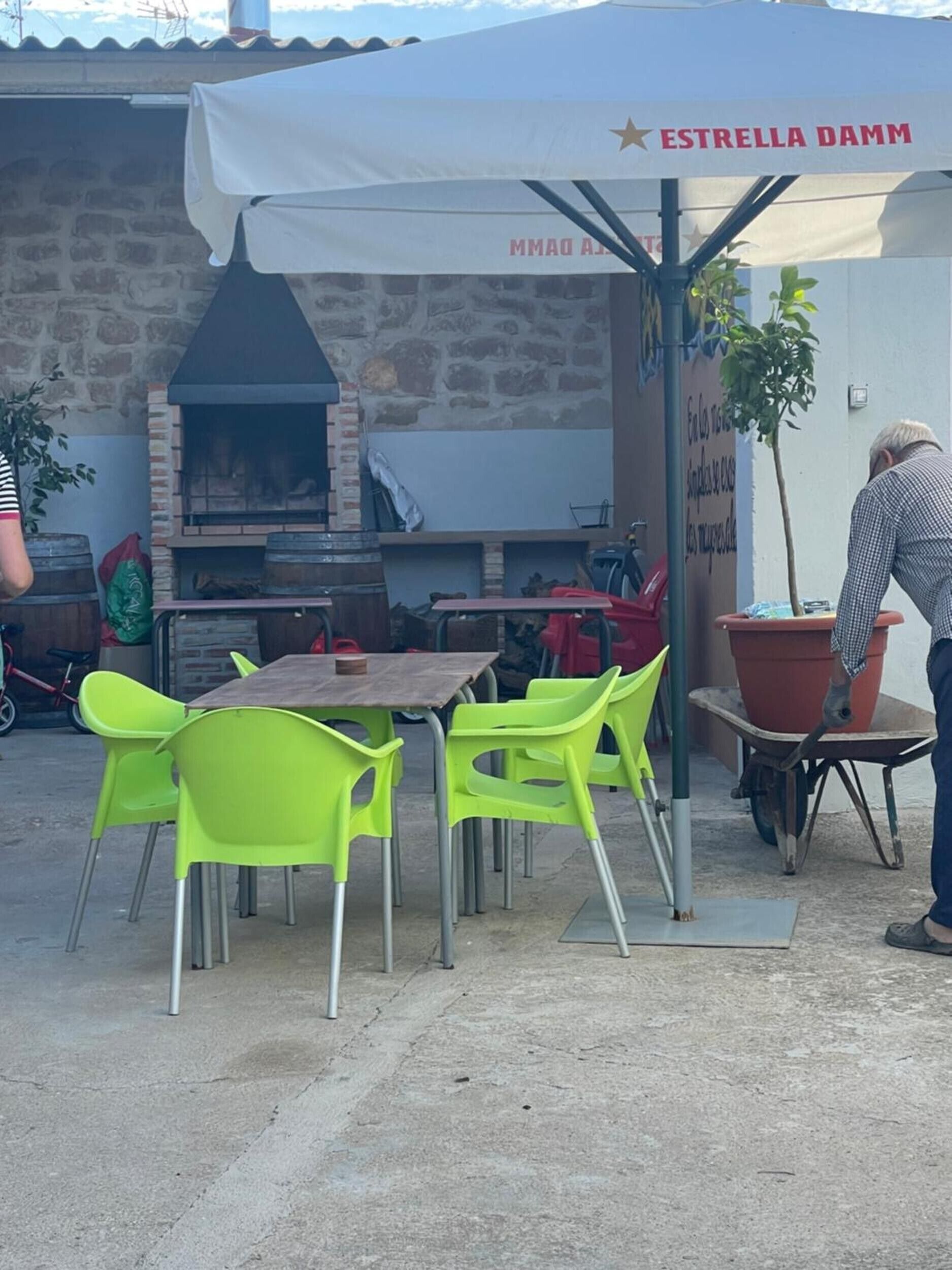 An outdoor dining area with a stone wall, a brick oven, and a covered seating area.