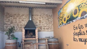 A rustic outdoor seating area with a brick oven, wooden barrels, and a mural on the wall. - Country House 'Fe' with Private Terrace, Private Garden and Balcony (Capdesaso)