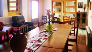 A dining area with a wooden table, chairs, a vase, and a floral table runner. - Country House 'Fe' with Private Terrace, Private Garden and Balcony (Capdesaso)