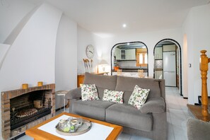 Ein Wohnzimmer mit Kamin, einer Couch, einem Couchtisch und einer Küche im Hintergrund.