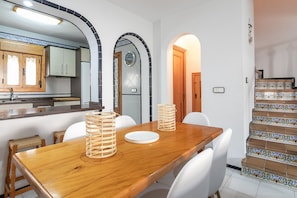 A dining area with a wooden table, white chairs, and two candle holders.