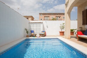 A swimming pool with two lounge chairs and potted plants.