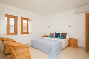 A bedroom with a bed, two bedside tables, a chair, and a door.