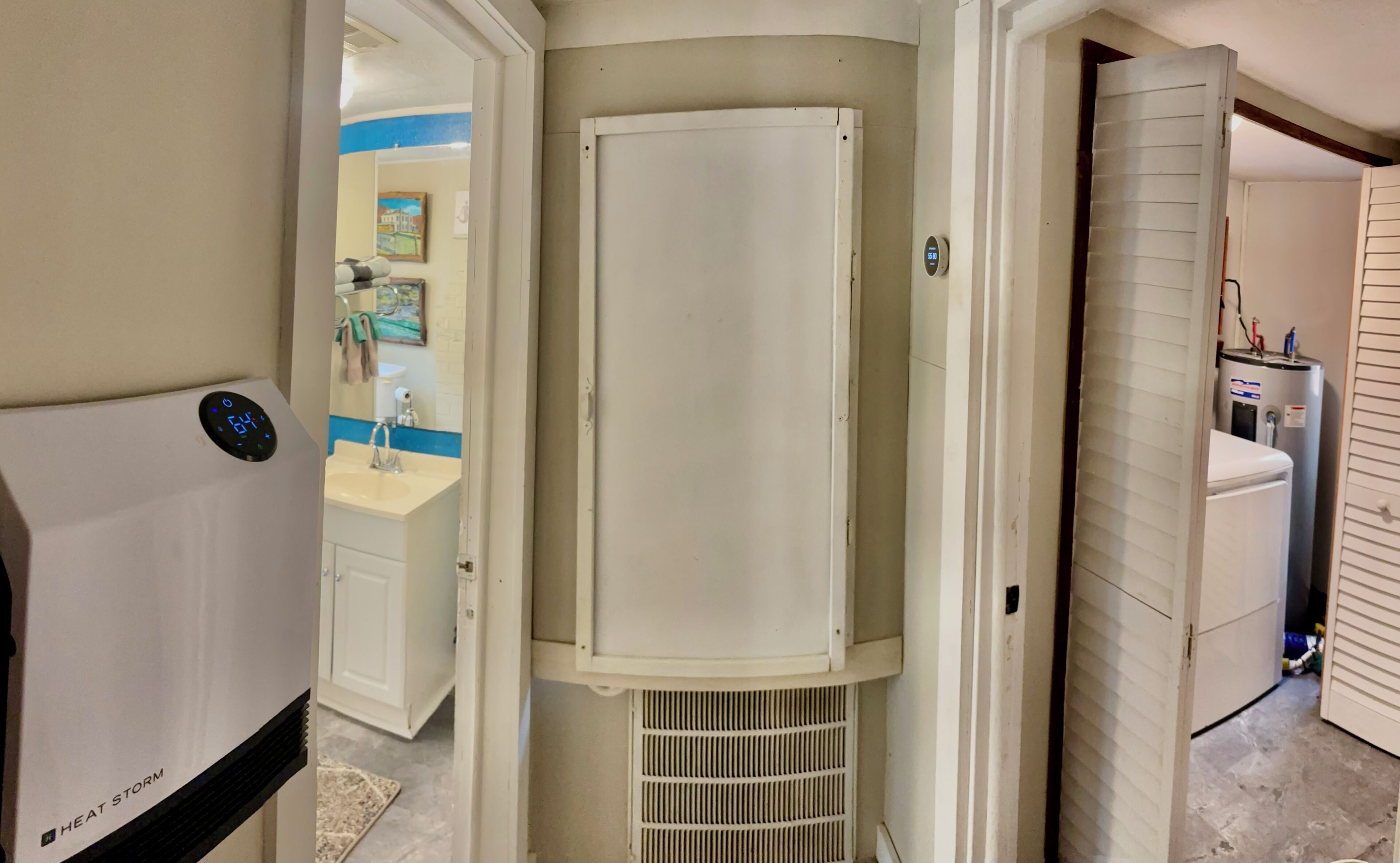 A bathroom with a white sink, mirror, and a heater unit labeled 'HEAT STORM'.