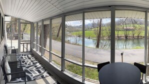 A covered porch with a view of a lake and road. - Charming 1-Bedroom, 1-bunk room, fishing in Gate City with Central Air, WiFi (Gate City)