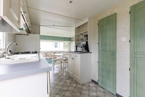 A kitchen with a sink, stove, and a dining area with chairs.