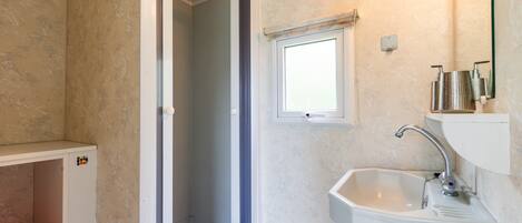 Un baño con ducha, lavamanos y ventana.