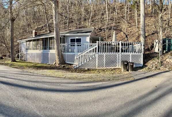 A cabin with a porch, a staircase, and a view of the surrounding forest.