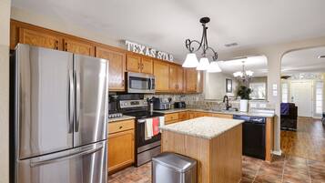 A modern kitchen with stainless steel appliances, wooden cabinets, and a granite countertop island.