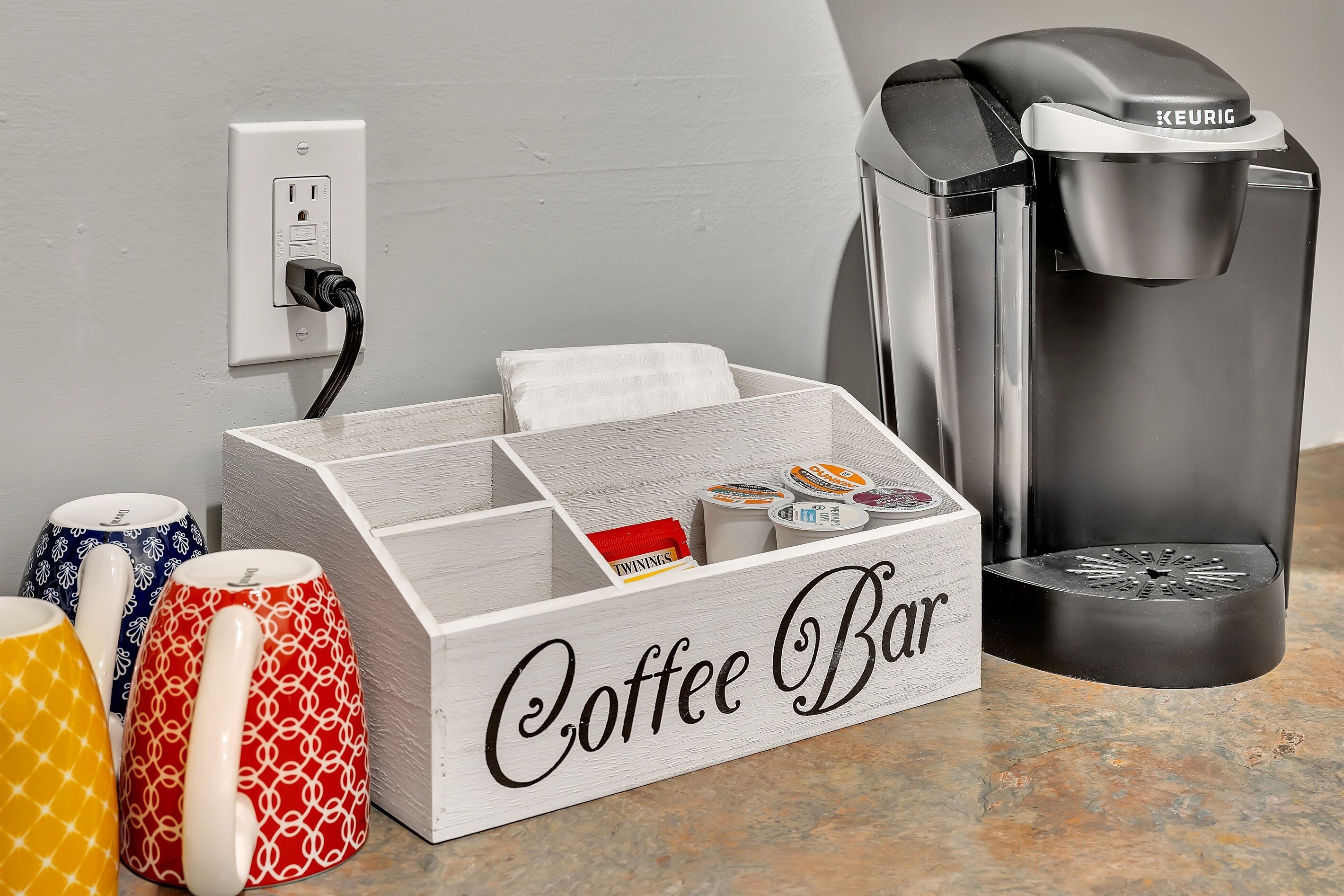 Una preparación para cafetería con una cafetera Keurig, un portavasos para tazas y una taza de café.